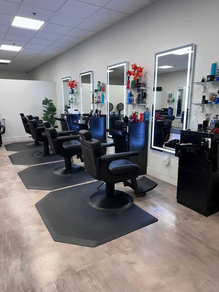 Barber chairs and mirrors in a modern, well-lit salon with shelves of hair products.